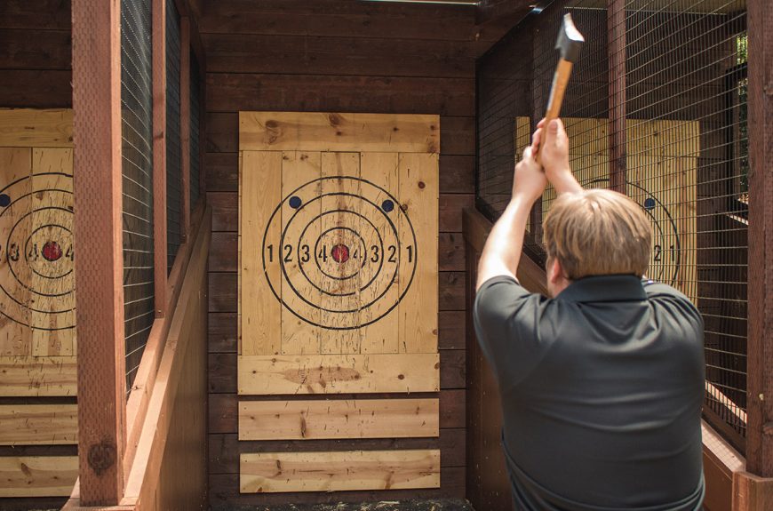 axe throwing coach showing how to throw an axe at the target